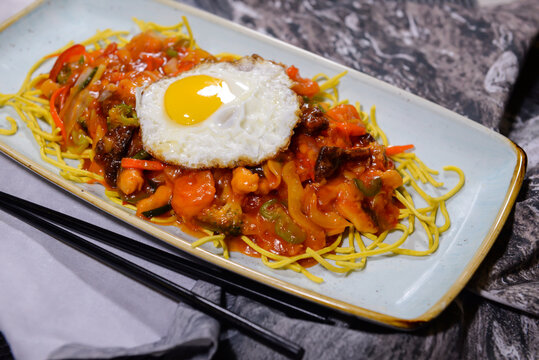 American Chopsuey with sunny side up egg, noodles, vegetables and chicken served in dish isolated on food table top view of middle east spices