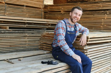 Industrial warehouse of a sawmill, an employee puts his hands on the finished products at the sawmill in the open air.