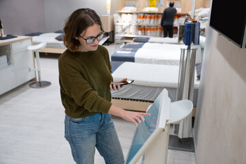 Woman with phone uses self-service kiosk in the shopping mall.