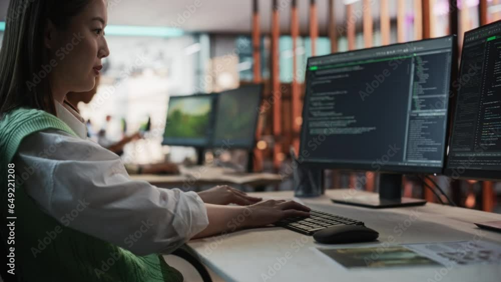 Aufkleber Female Asian Game Programmer Coding On Desktop Computer In Game Development Studio Diverse Office. Focused Woman Writes Lines Of Code, Does AI Engineering For New Immersive 3D Survival Video Game.