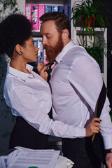 tempting african american businesswoman undressing bearded colleague in office, side view