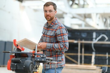 Wood cutting table with electric circular saw. Professional carpenter in uniform cutting wooden board at sawmill carpentry manufacturing . Sawing machine