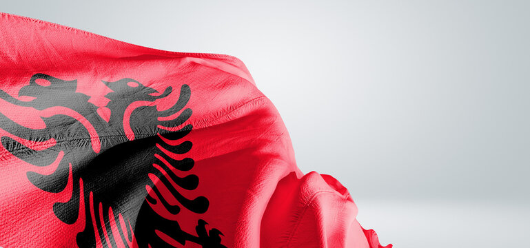 Albania national flag cloth fabric waving on beautiful sky Background.