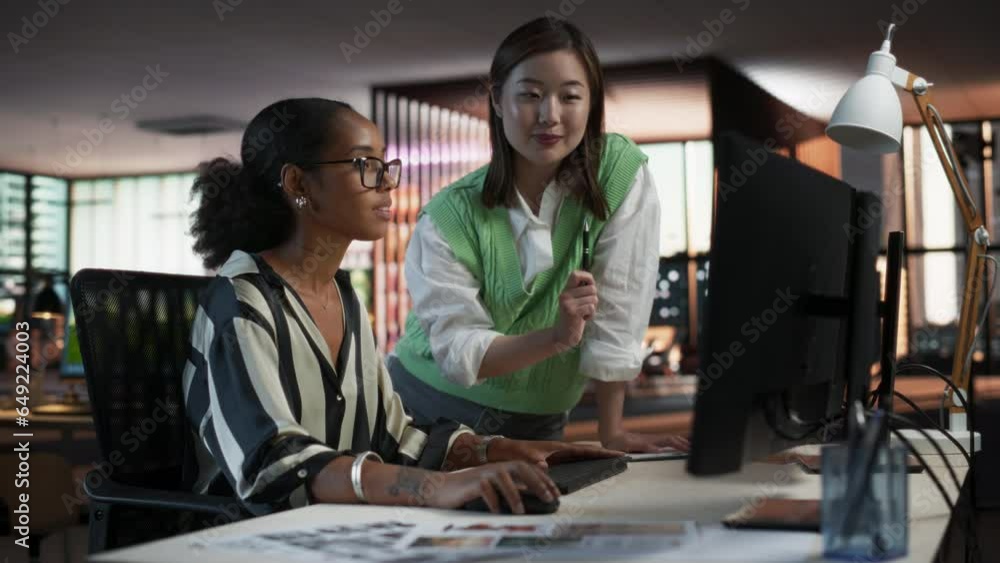 Aufkleber Black Female Game Designer Using Desktop Computer With Animation Software And Talking to Asian Female Project Manager in Game Development Studio Office. Diverse Colleagues Discussing New RPG Game.