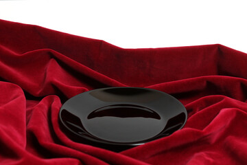 The Black Plate on a Red Fabric on a White Background
