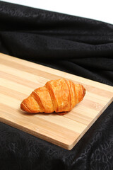 The Croissant on a Wooden Board on a Black Fabric Background