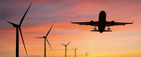 Silhouette of landing plane with wind turbines. Clean mobility concept
