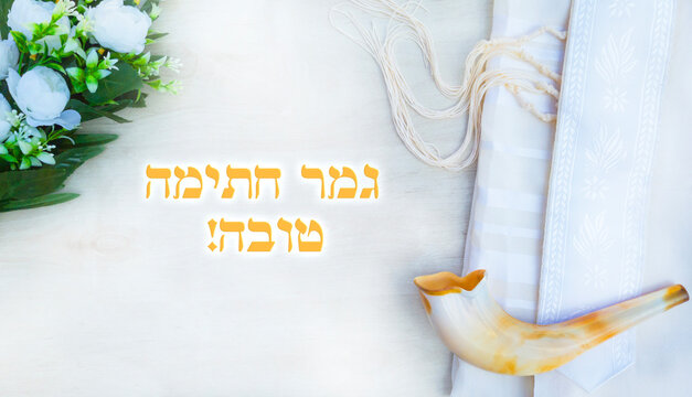 Translation title: May you be signed and sealed in the book of life. in Hebrew. 
A shofar is placed on a tallit and siddur book on a white background. greeting card and Yom Kippur Rosh Hashanah 
