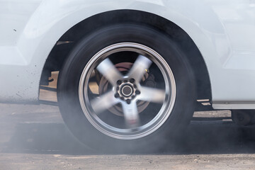 Close up car wheel with smoke on the asphalt road speed track, Car wheel drifting and smoking on track, Car wheel spinning.