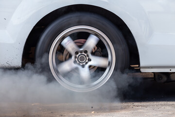 Close up car wheel with smoke on the asphalt road speed track, Car wheel drifting and smoking on track, Car wheel spinning.