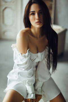 Sensual brunette young woman in white dress. Soft light portrait