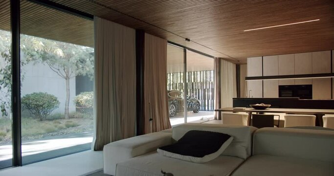 Modern interior of cottage house, room with comfort couch and pillow, dining table with chairs, kitchen space with household appliances, panoramic windows or glass wall and parked car outside