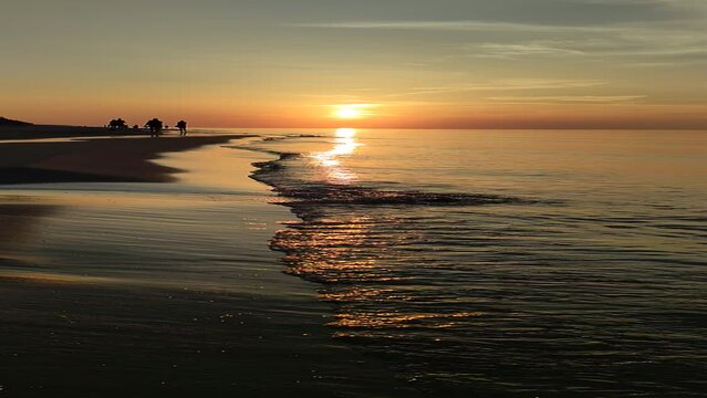 Zach&oacute;d słońca nad linią brzegową morza bałtyckiego. Zachodzące słońce nad plażą  Kadr poziomy. 