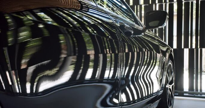 Closeup of black modern car with reflection standing in garage. Vehicle parked at house parking