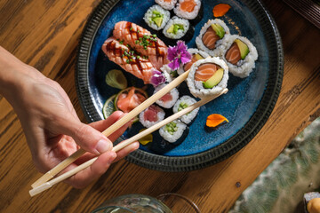 Person taking sushi roll with salmon and avocado