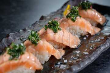 Appetizing nigiri sushi with salmon slices garnished with fresh herbs and salt served on marble...