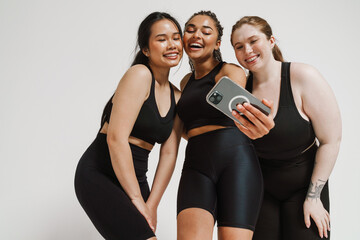 Three cheerful women taking selfie isolated over white background