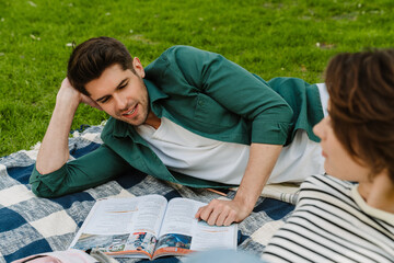 Man reading while laying with female friend in park