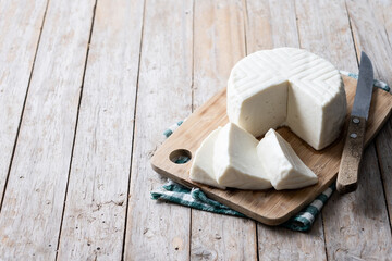 Sliced fresh white cheese from cow's milk on wooden table. Copy space
