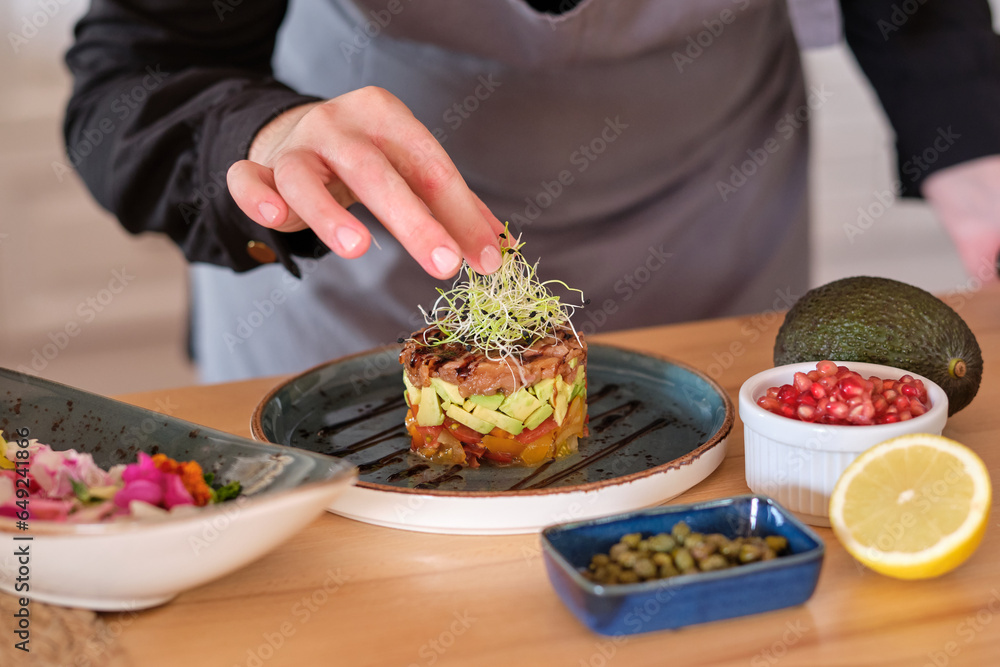 Wall mural Chef garnishing tartar with microgreen