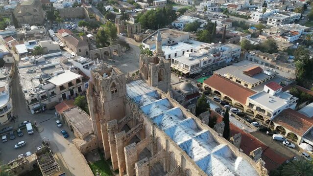 Tilting aerial view of imposing gothic cathedral, with an added minaret on the side. Now Lala Mustafa mosque. Architecture and history in Famagusta, Northern Cyprus. 
