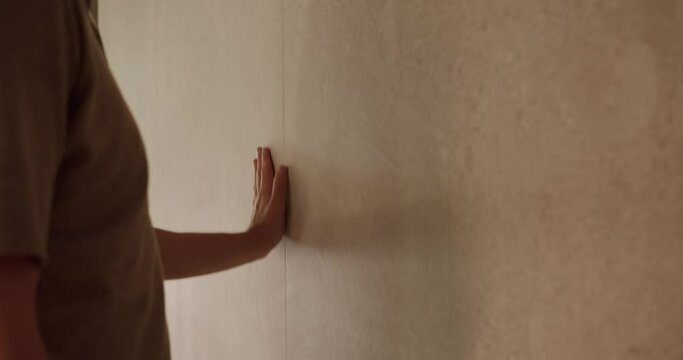 Cropped view on person hand touching new ceramic tile on wall at luxury apartment after renovation. High quality of decorative marble tile using in room interior