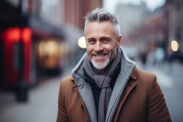 Obraz premium Portrait of a handsome mature man with grey hair wearing coat and scarf in the city.