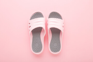 Pink gray foam slippers on light pink table background. Pastel color. Closeup. Summer footwear. Top...