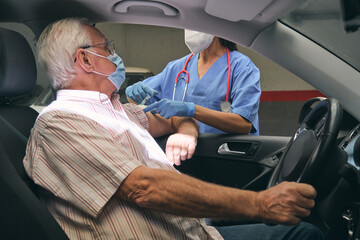 Unrecognizable nurse inoculating senior driver in car