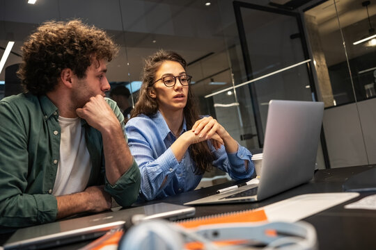Two programmers and engineers work alongside their colleagues in an office, collaborating on coding and driving technological innovation.	
