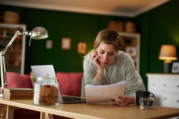 Mid adult woman examining her bank statement at home office