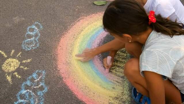 Children draw a rainbow with chalk on the pavement. Selective focus.