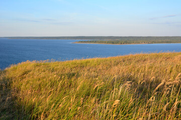 hill with dry yellow grass and blue river on horizon copy space