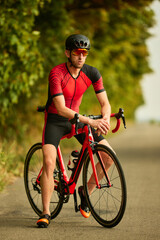 Professional triathlete training outdoors, wearing sportswear and helmet, riding bike along the road. Concept of professional sport, triathlon preparation, competition, athleticism