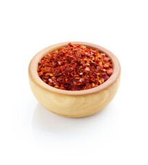 Spicy crushed pepper in wooden bowl isolated on white background