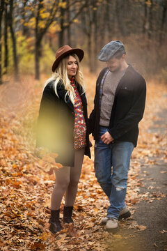 Full length image of a  couple walking in the park, girlfriend is pregnant, dressed in autumn clothes and hat, warm colors. Family concept.