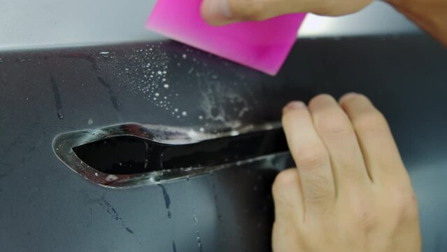 Closeup of Process of applying a protective PPF film to a car. Hands of a professional applying a protective film of laminate. Closeup