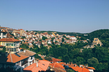 Fototapeta na wymiar view of summer heat forest surrounded mountain town in bulgaria with many beautiful colorful orange houses 