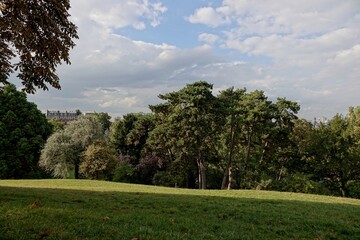 Fototapeta na wymiar Vue du parc des Buttes-Chaumont avec ciel bleu et gros nuages blancs 