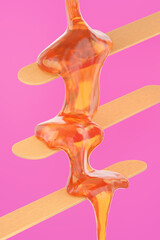 Sugaring paste flows on wooden sticks for hair removal procedure. Cosmetic spatula with liquid sugar syrup on pink background. 3d render - 649267896