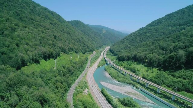 Aerial of a highway in between the mountains and the river. Amazing nature scenery
