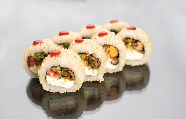 Sushi rolls in sesame seeds on white background with reflection, space for text. Japanese food