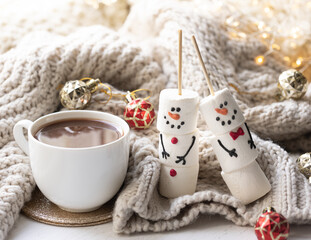 Winter composition with a cup of cocoa and marshmallows on a blurred background.