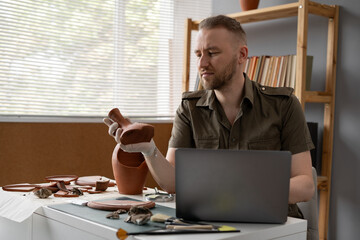 Archaeological digging. Male archaeologist doing research, using laptop computer, analysing ancient...