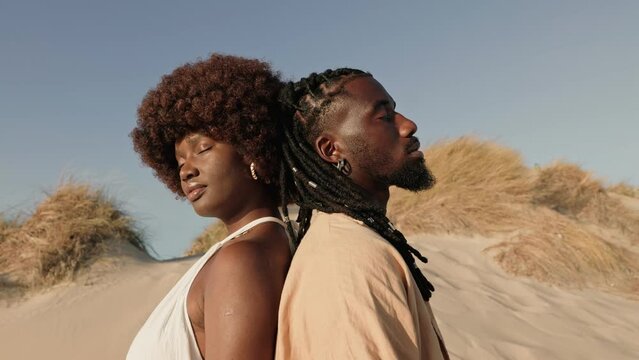A conceptual artistic video featuring a beautiful black woman and an African male leaning back-to-back with closed eyes, symbolizing a profound connection