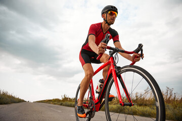Competitive man, triathlete riding bicycle on road outdoors, training for marathon. Bottom view....