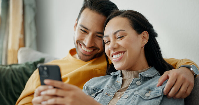 Couple, smile and talking on sofa with phone for social media post, subscription and reading funny notification. Happy man, woman and hug with smartphone for meme, games app and relax in living room