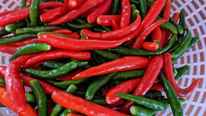 Close-up of stacked fresh raw red and green peppers on basket 
