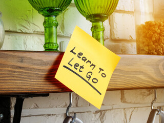 Sticker with the inscription Learn to let go is attached to your home shelf.