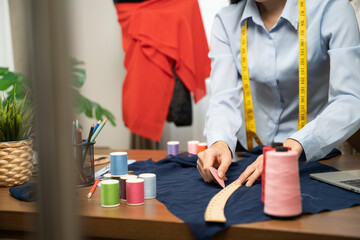 Female clothing designer placing pattern on fabric in home.